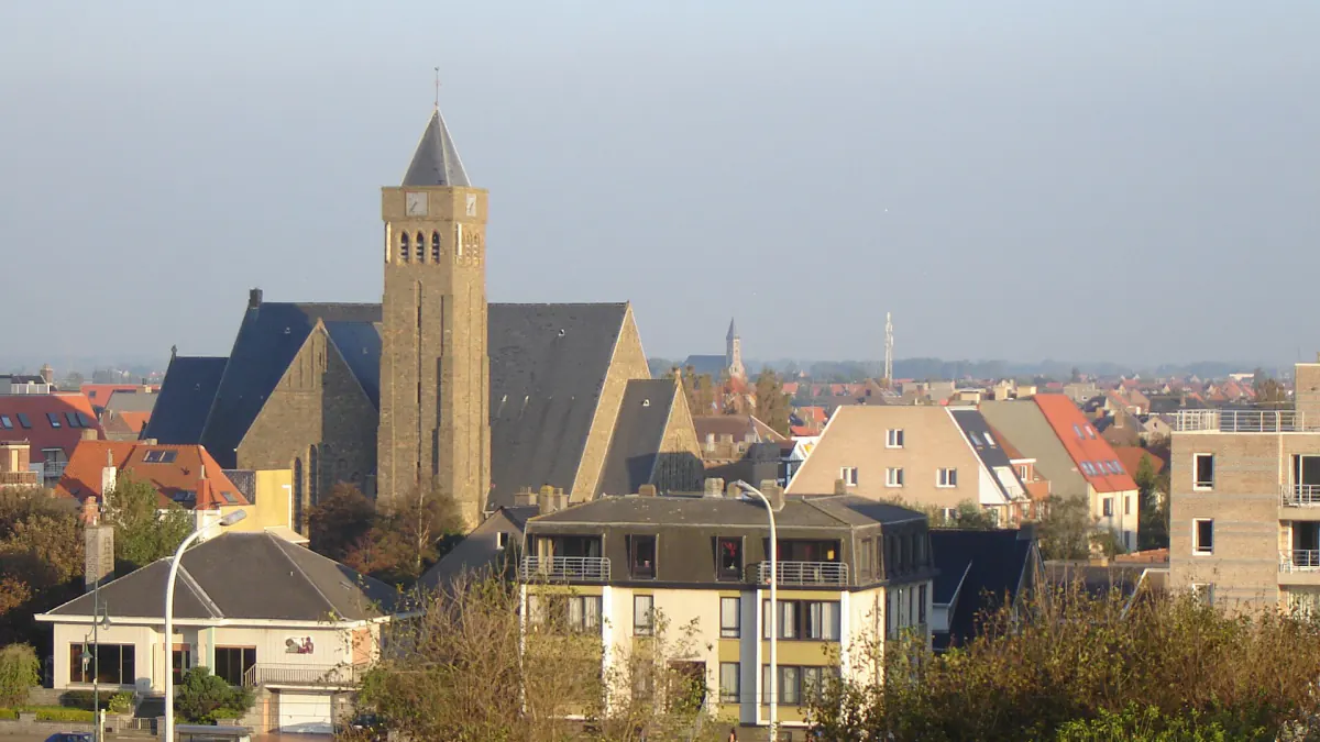 Église en pierre de Bredene dominant les toits et les maisons, vue depuis les dunes