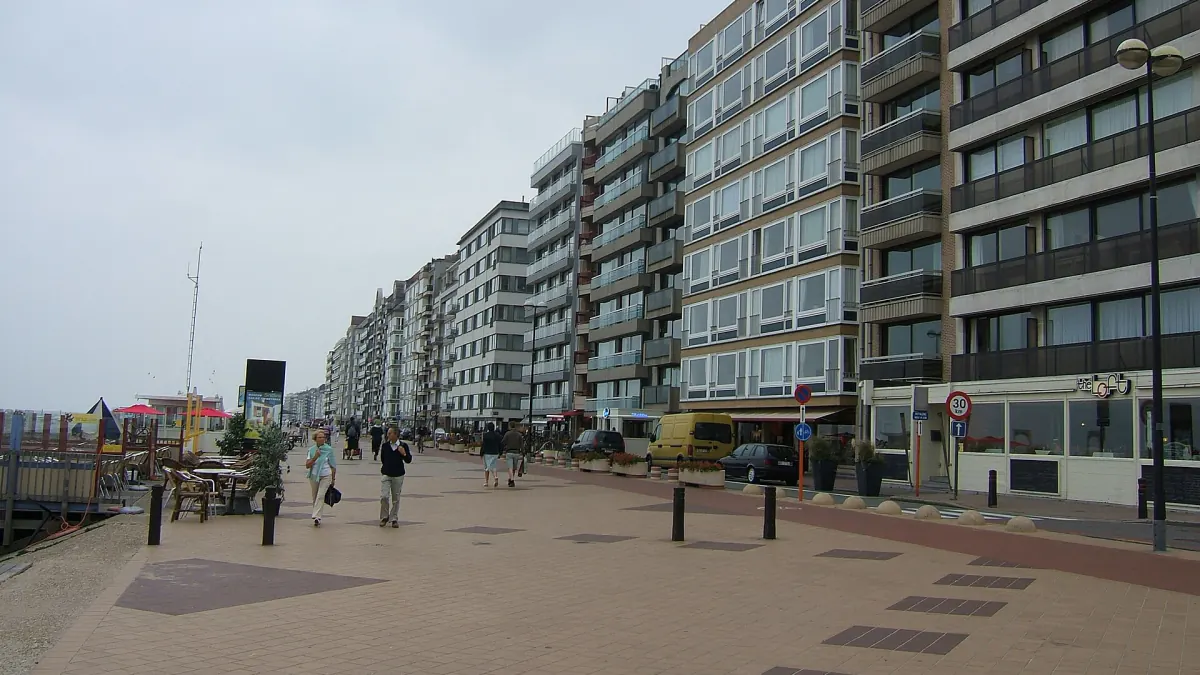 Digue piétonne de Knokke-Heist bordée de hauts immeubles, avec quelques promeneurs