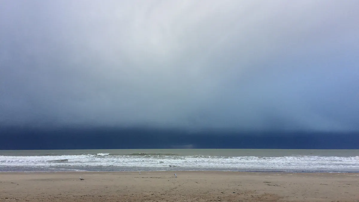 Mer du Nord à Ostende : vagues sur la plage de sable sous un ciel lourd d'averse