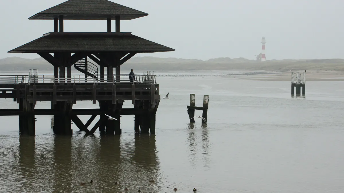 Ponton en bois à toit pagode dans le chenal du port de Nieuport, dans la brume